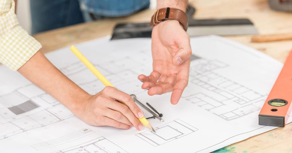 Eigentümer und Bauherr sowie Architekt planen über einem Bauplan den Bau, beziehungsweise den Umbau, einer Immobilie | Immobilienkauf