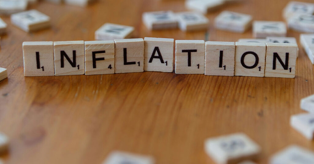 Auf einem Tisch liegt aus Scrabble-Buchstaben gelegt das Wort "Inflation" als Symbol für Immobilieninvestments während einer Inflation | Immobilieninvestment